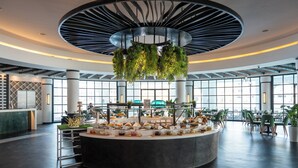 A modern hotel lobby with a central food display, large windows, and a circular ceiling design. - Millennium Lakeview Residence (Dubai)