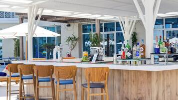 A bar area with wooden chairs, a counter with various bottles, and a modern ceiling design.
