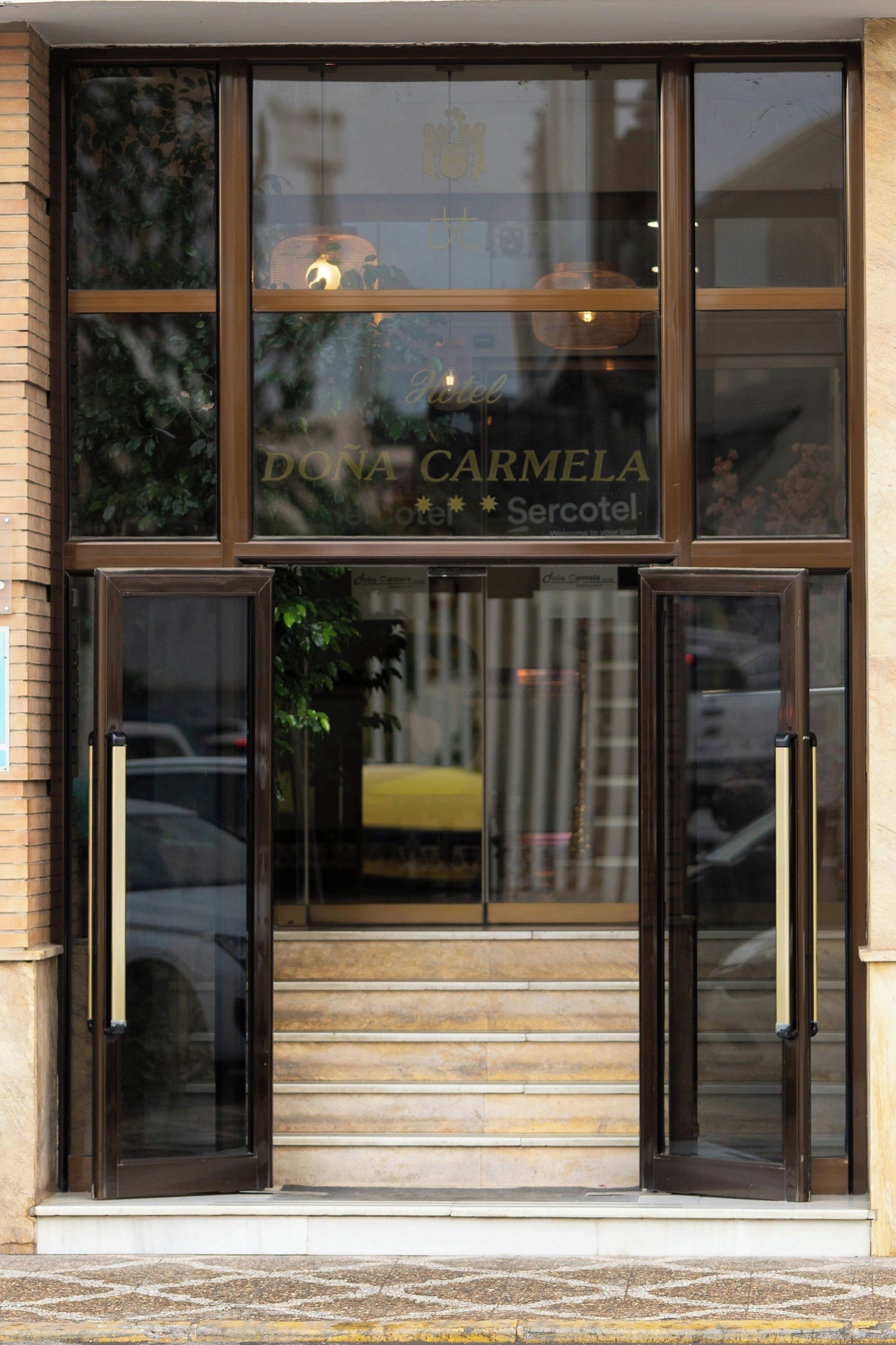 A hotel entrance with double doors and a visible name 'DONA CARMELA'.
