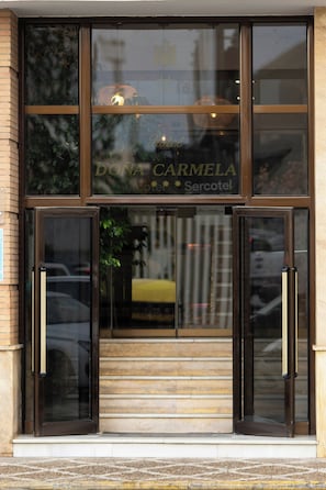 Een hotelentree met dubbele deuren, met de naam 'DONA CARMELA' duidelijk zichtbaar.