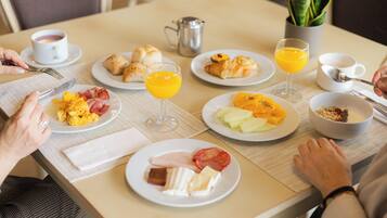 Et morgenbord med tallerkener med mad, en kaffekop og et kande appelsinjuice på et bord.