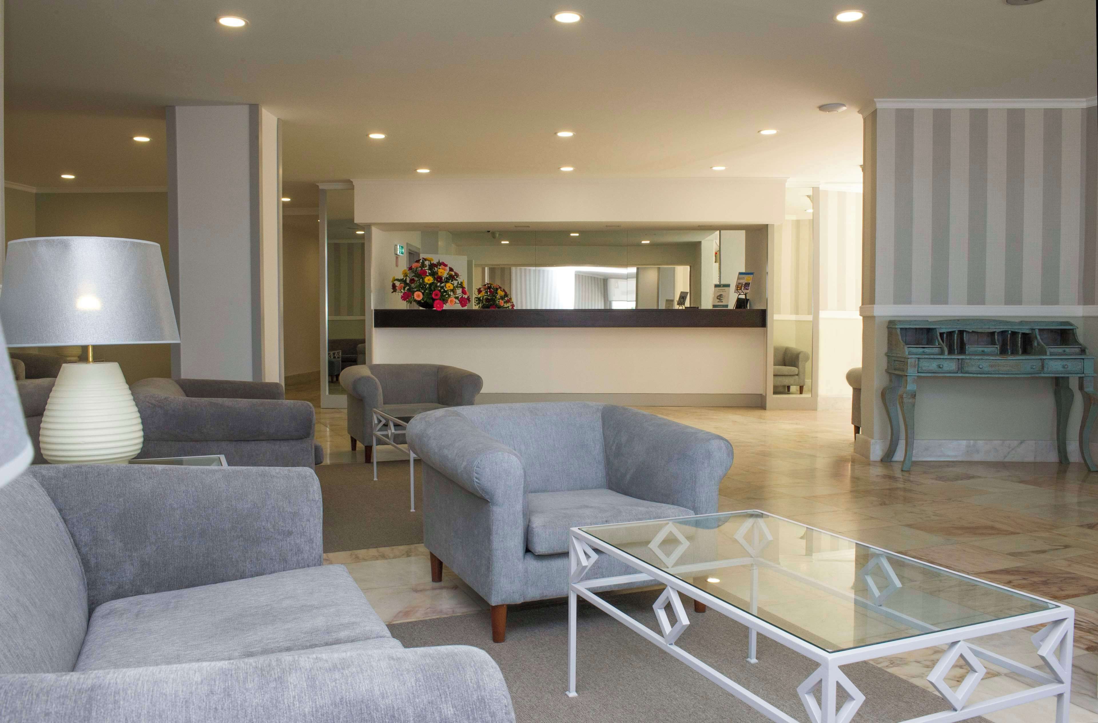 A modern living room with grey sofas, a glass coffee table, and a large lamp.