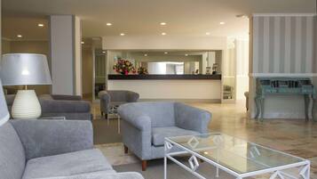A modern living room with grey sofas, a glass coffee table, and a large lamp.