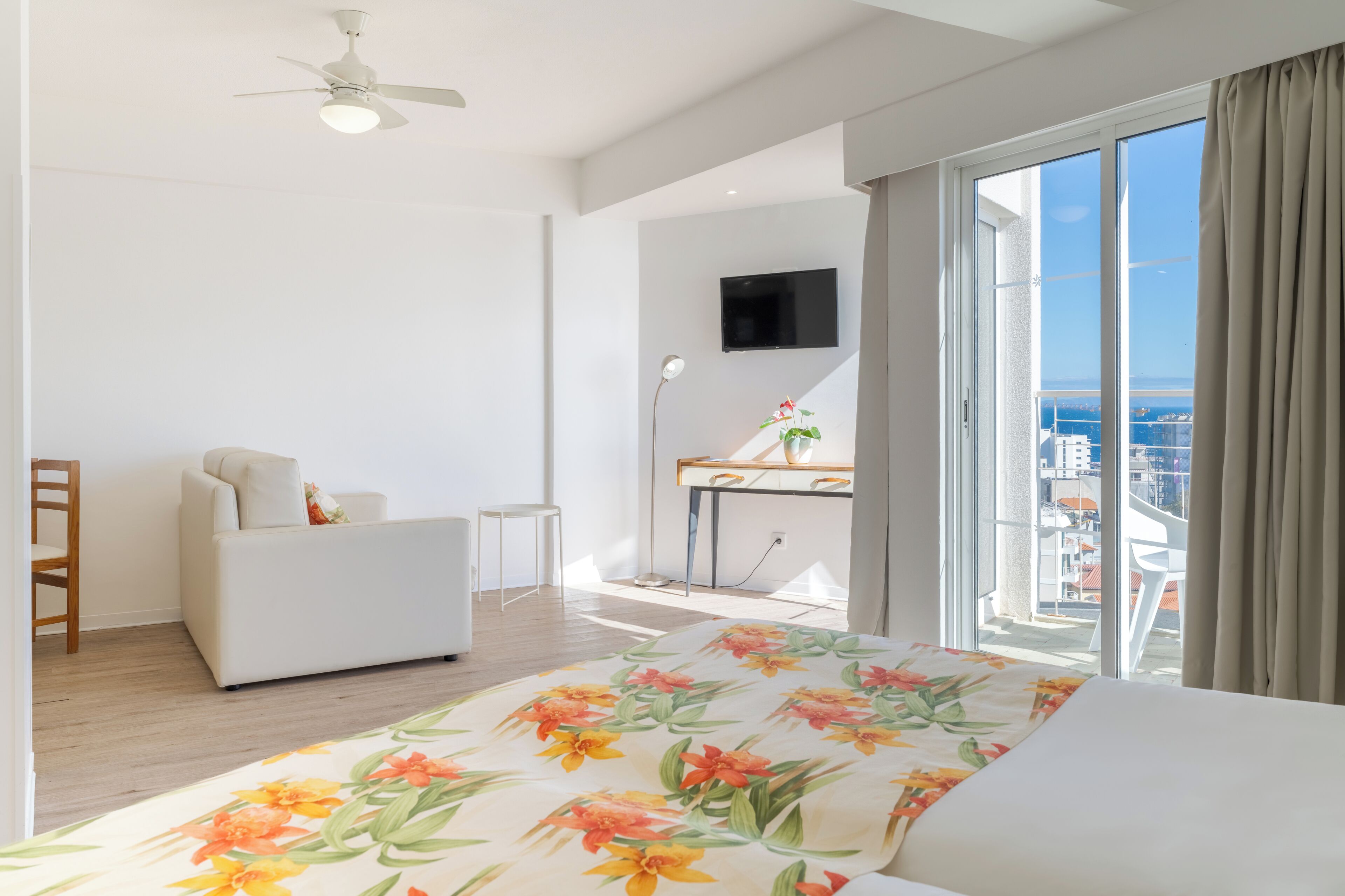 Un dormitorio moderno con una cama grande, un escritorio, una silla y un televisor.