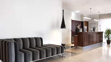 Een moderne receptie met een bank, een receptiebalie en een potplant.