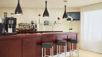 Een moderne keuken met een bar, voorzien van koffieapparaten, een televisie en decoratieve objecten.