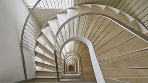 A spiral staircase with a modern design, featuring a series of steps that ascend in a circular pattern. - Exe Plaza Delicias (Zaragoza)