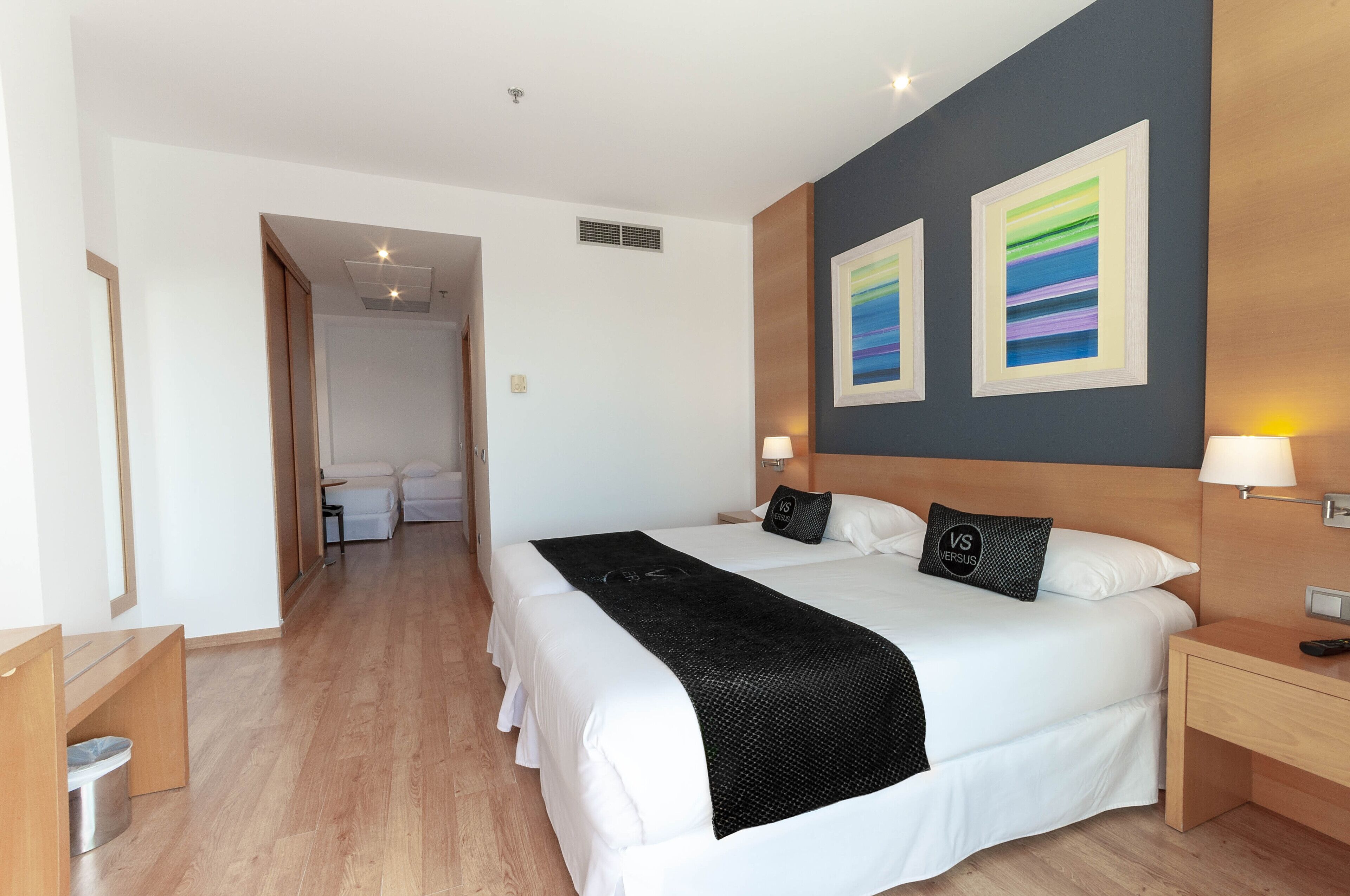 Quarto de hotel com uma cama grande, duas mesas de cabeceira e piso de madeira.