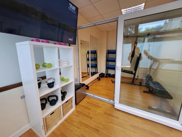 A gym with wooden floors, weightlifting equipment, and a mirrored wall. - Hotel Ciudad Cangas De Onis (Cangas de Onis)