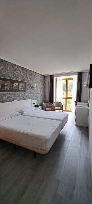 A hotel room with a large bed, a desk, a chair, and a television. - Hotel Ciudad Cangas De Onis (Cangas de Onis)