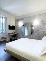 Una camera da letto con un letto, una scrivania, una sedia, una televisione e una finestra.