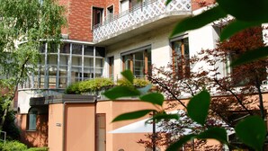 A multi-story building with a brick facade, a balcony with a lattice railing, and outdoor seating with chairs and tables. - Hotel Tiziano (Milan)