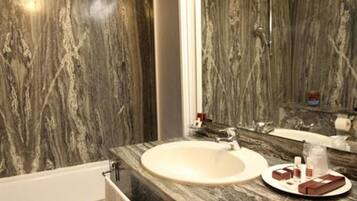 A bathroom with a marble sink, a mirror, and toiletries on the counter.