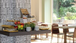 A dining area with a buffet setup, including fruits, plates, and glasses. - Hotel Tiziano (Milan)