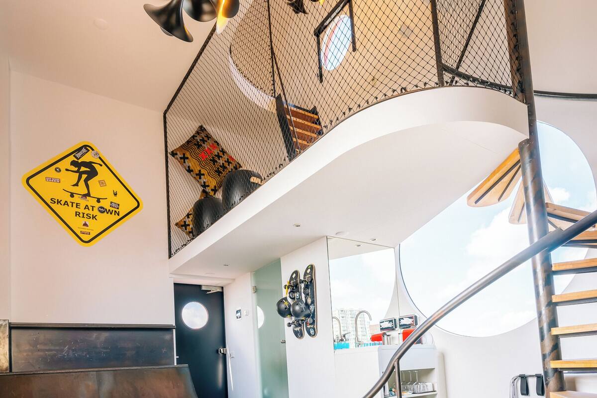 Un intérieur moderne agrémenté d’un escalier en colimaçon original, d’une porte bien visible et d’un porte-casque fixé au mur.