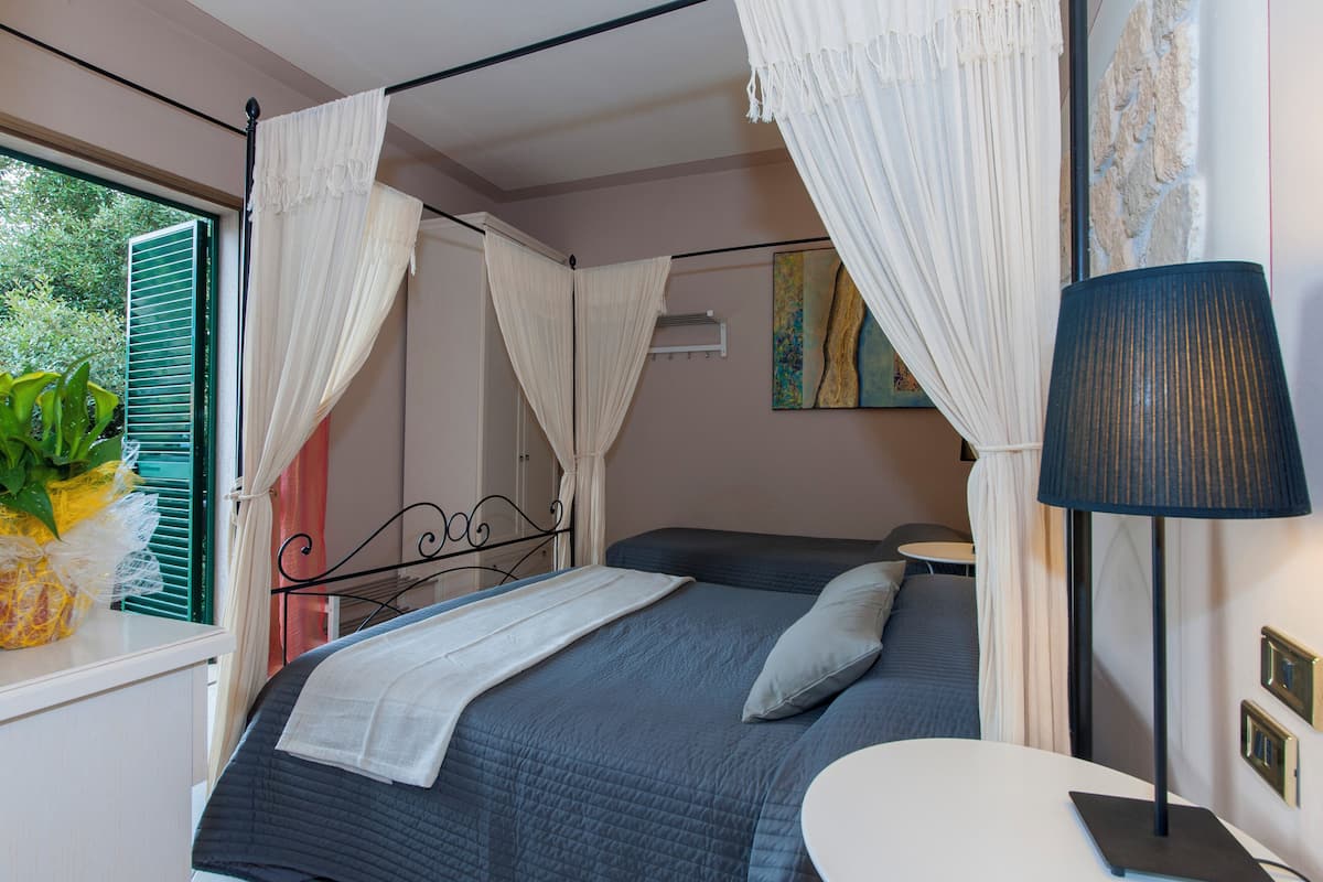 A bedroom with a bed, a bedside table, a lamp, and a window with curtains.
