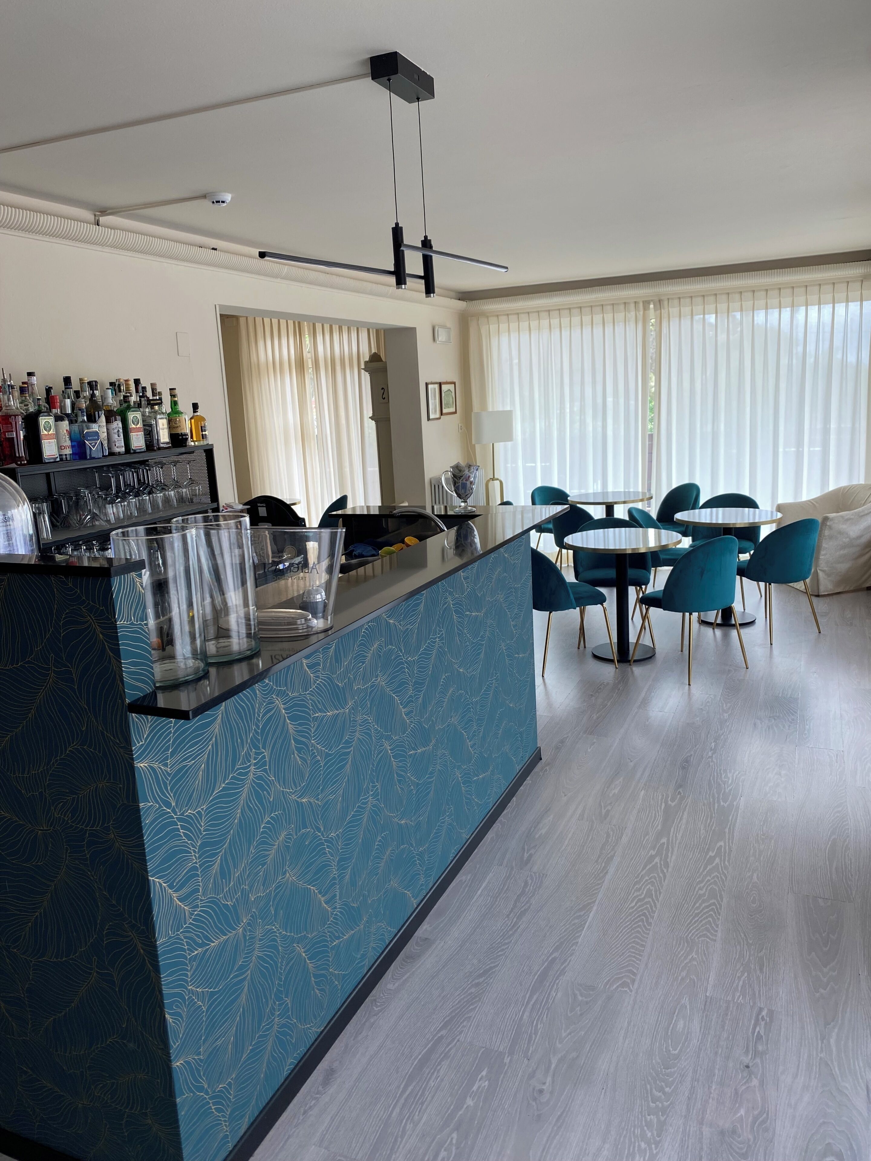 Una habitación de hotel moderna con una zona de bar, comedor y un amplio ventanal con cortinas.