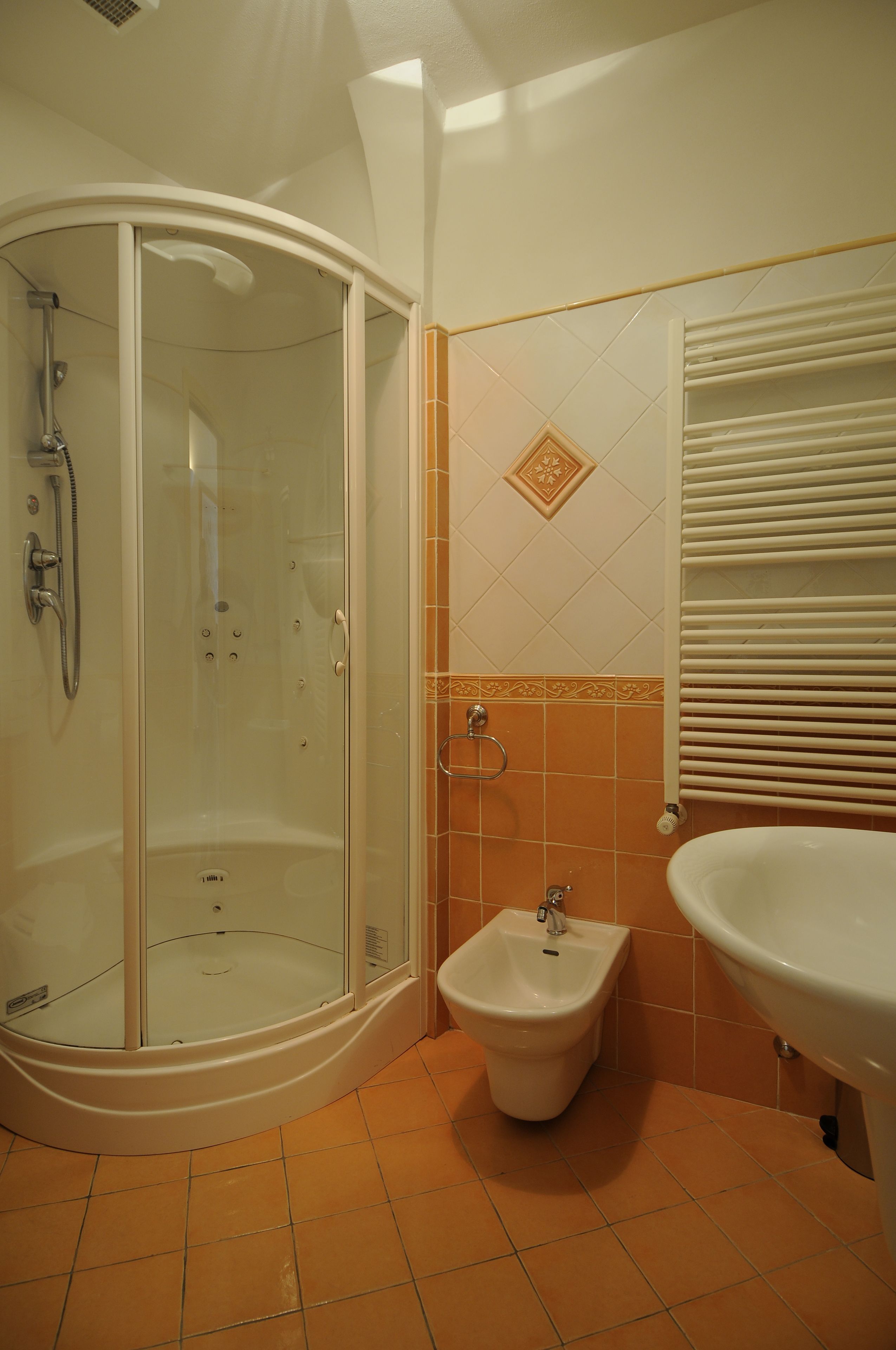 A bathroom with a glass-enclosed shower, a bidet, and a sink.