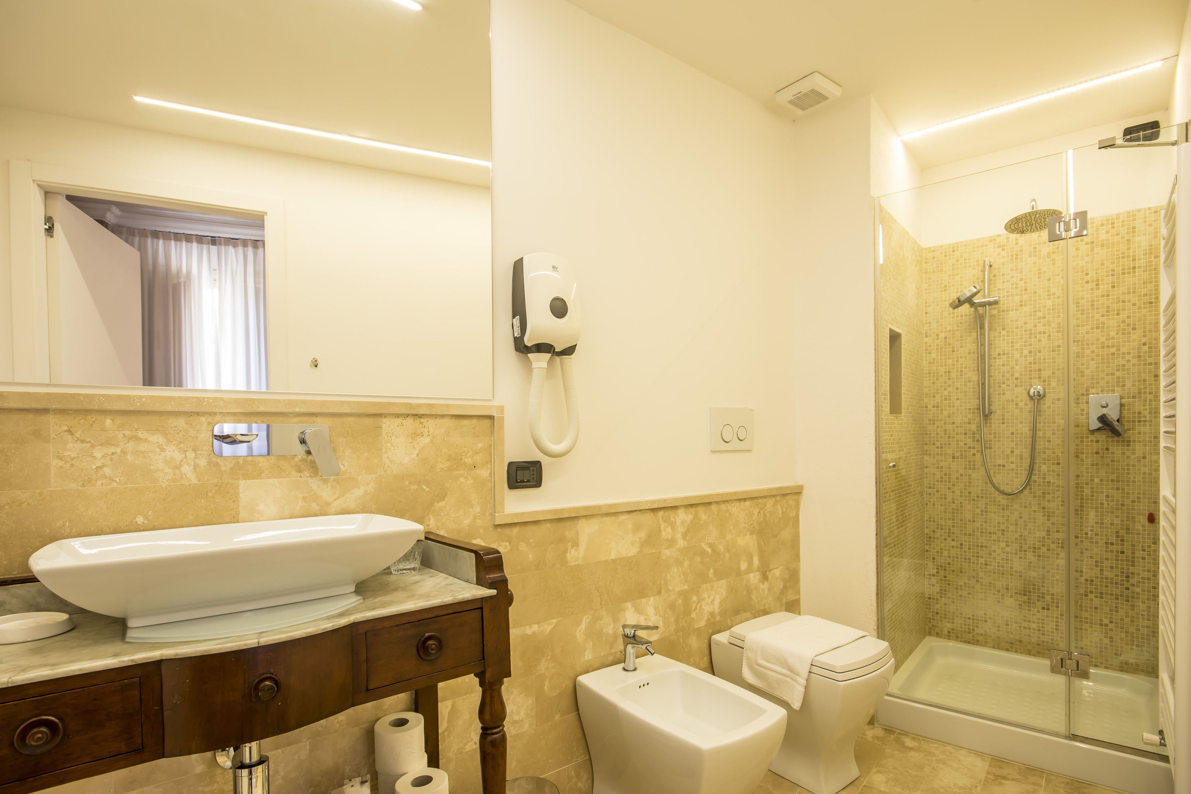 Une salle de bain moderne dotée d’un grand lavabo, d’un bidet, de toilettes et d’une douche à parois de verre.