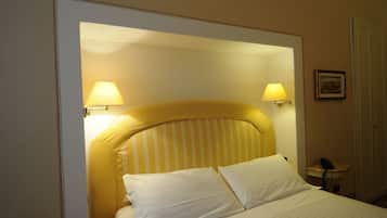 A hotel room with a bed, two bedside lamps, a telephone, and a framed picture on the wall.