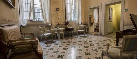 A spacious room with a floral floor pattern, a grand piano, and a chandelier.