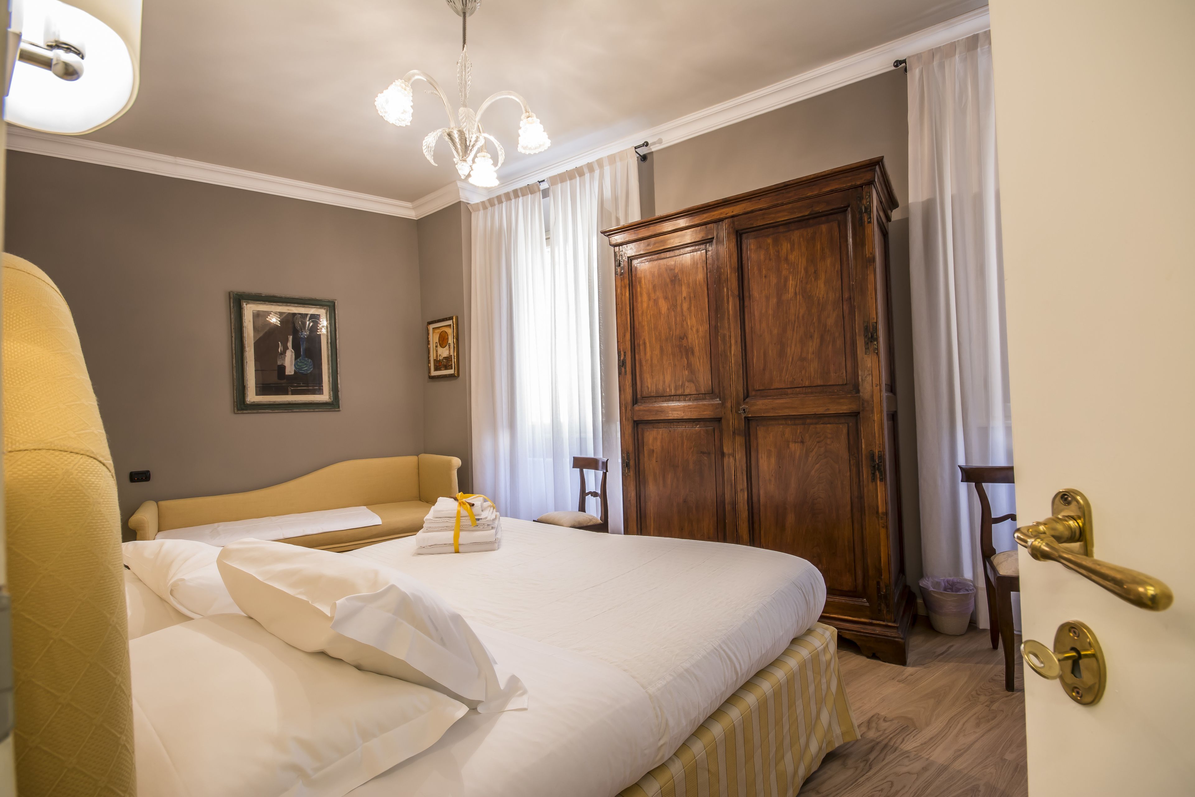Een hotelkamer met een groot bed, een houten garderobe, een stoel en een nachtkastje.