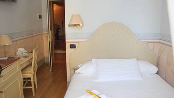 Una habitación de hotel con una cama, un escritorio, una silla y un televisor montado en la pared.