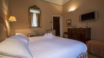 A hotel room with a large bed, a desk, a dresser, a television, and a mirror.
