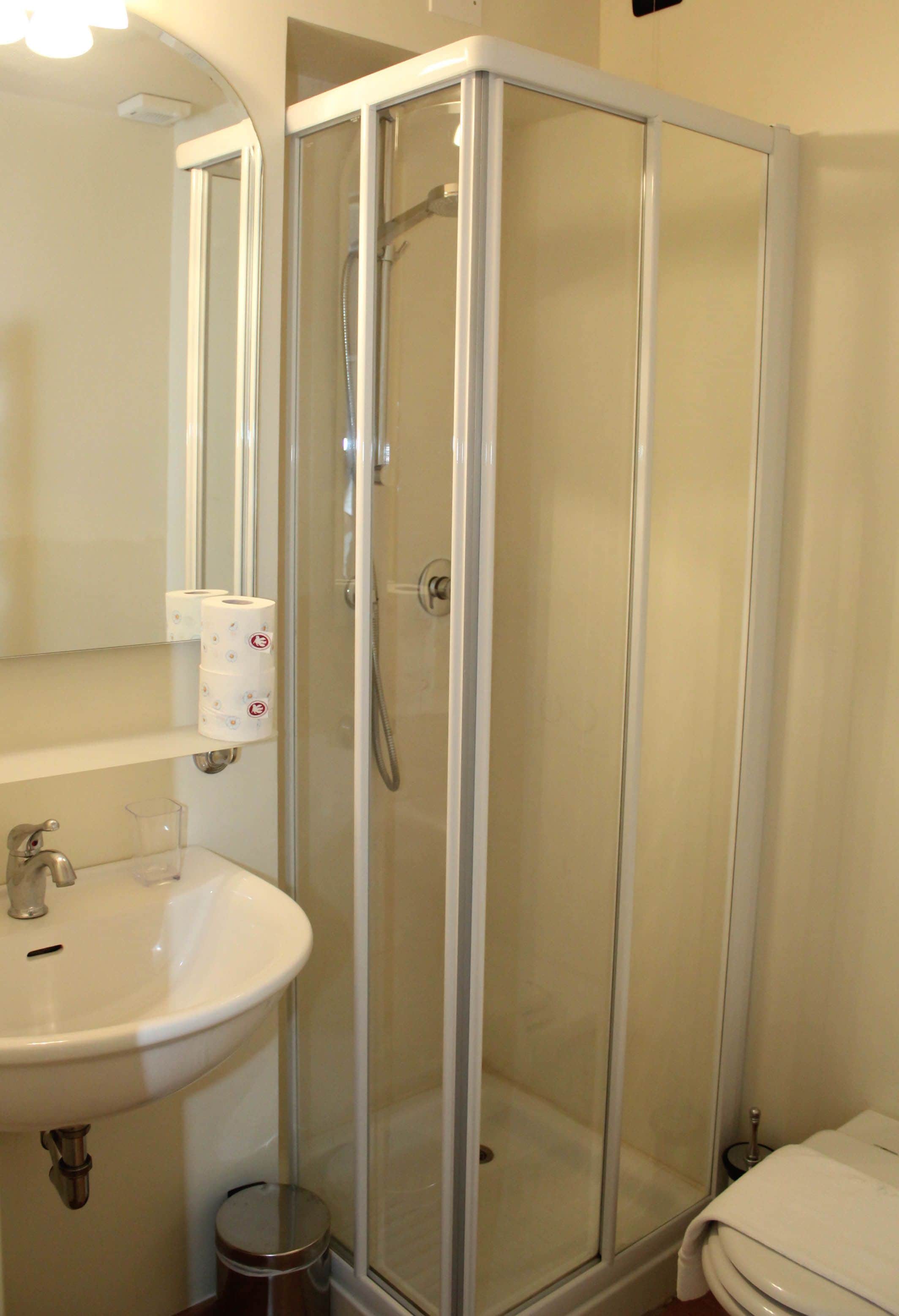 A bathroom with a glass-enclosed shower, a sink, and a toilet.
