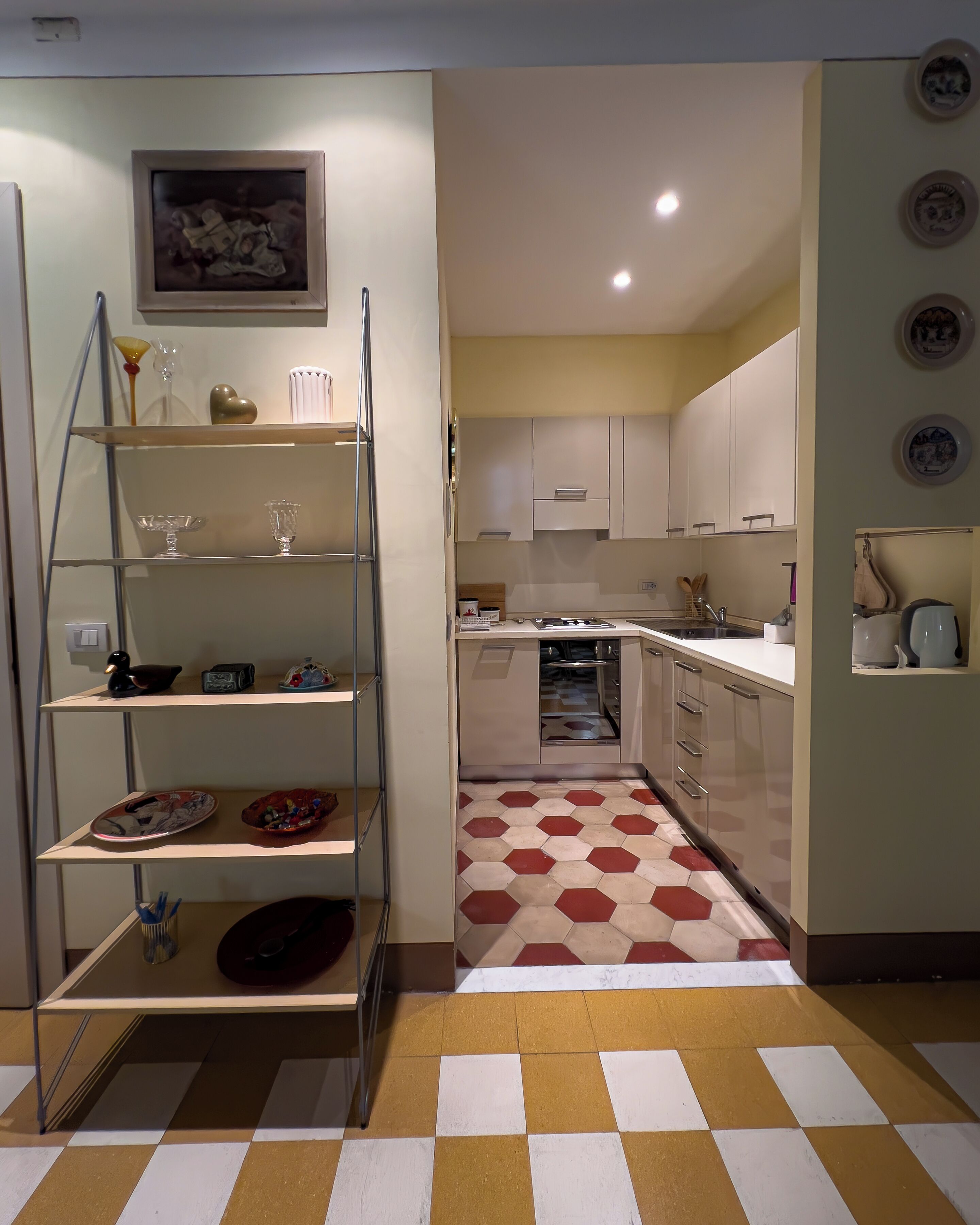 Una cocina con piso de tablillas, una estantería metálica y un cuadro en la pared.
