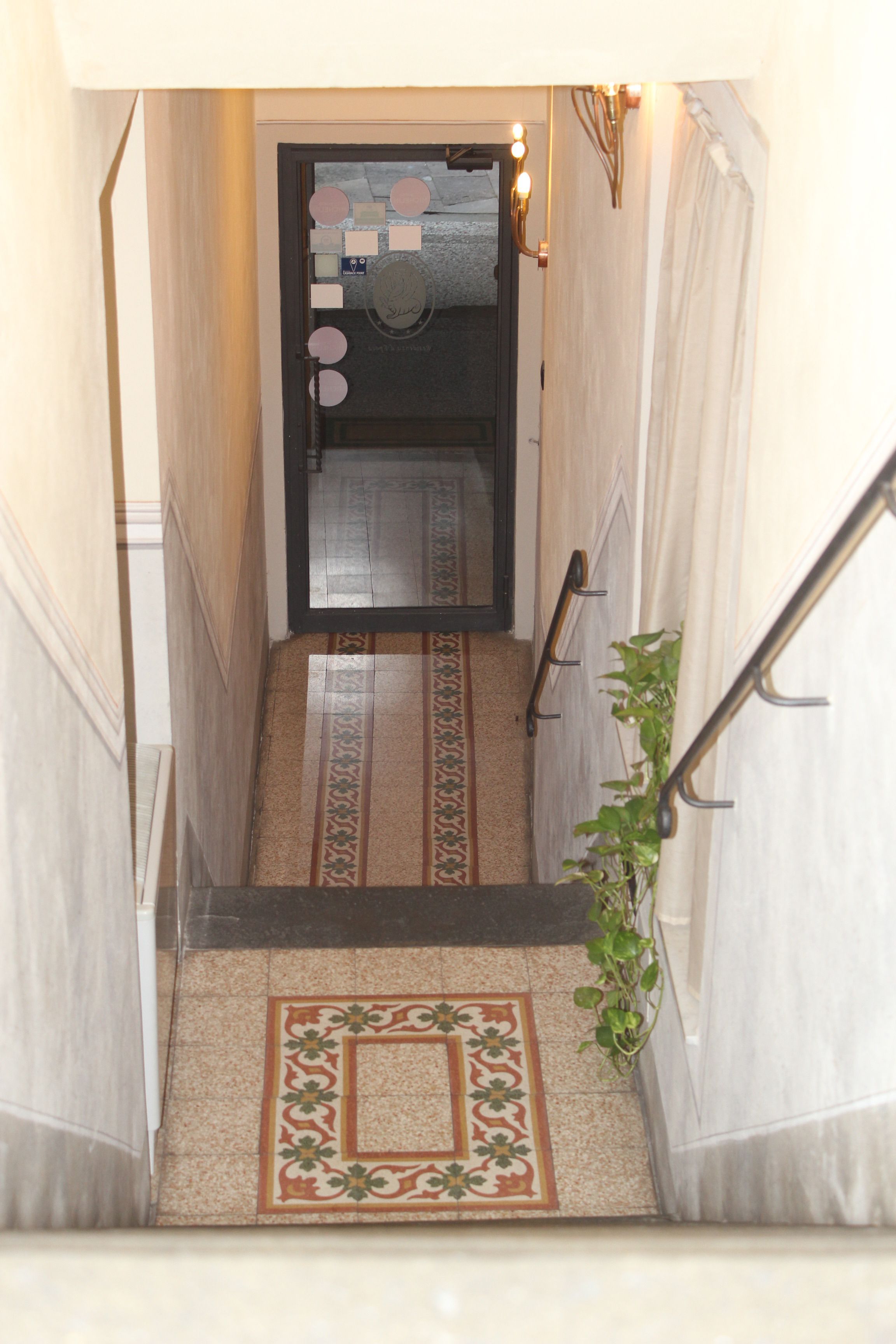 A narrow hallway with a patterned carpet leading to a door with a decorative mat.