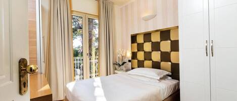 Un dormitorio con cama, armario, mesita de noche y ventana con cortinas.