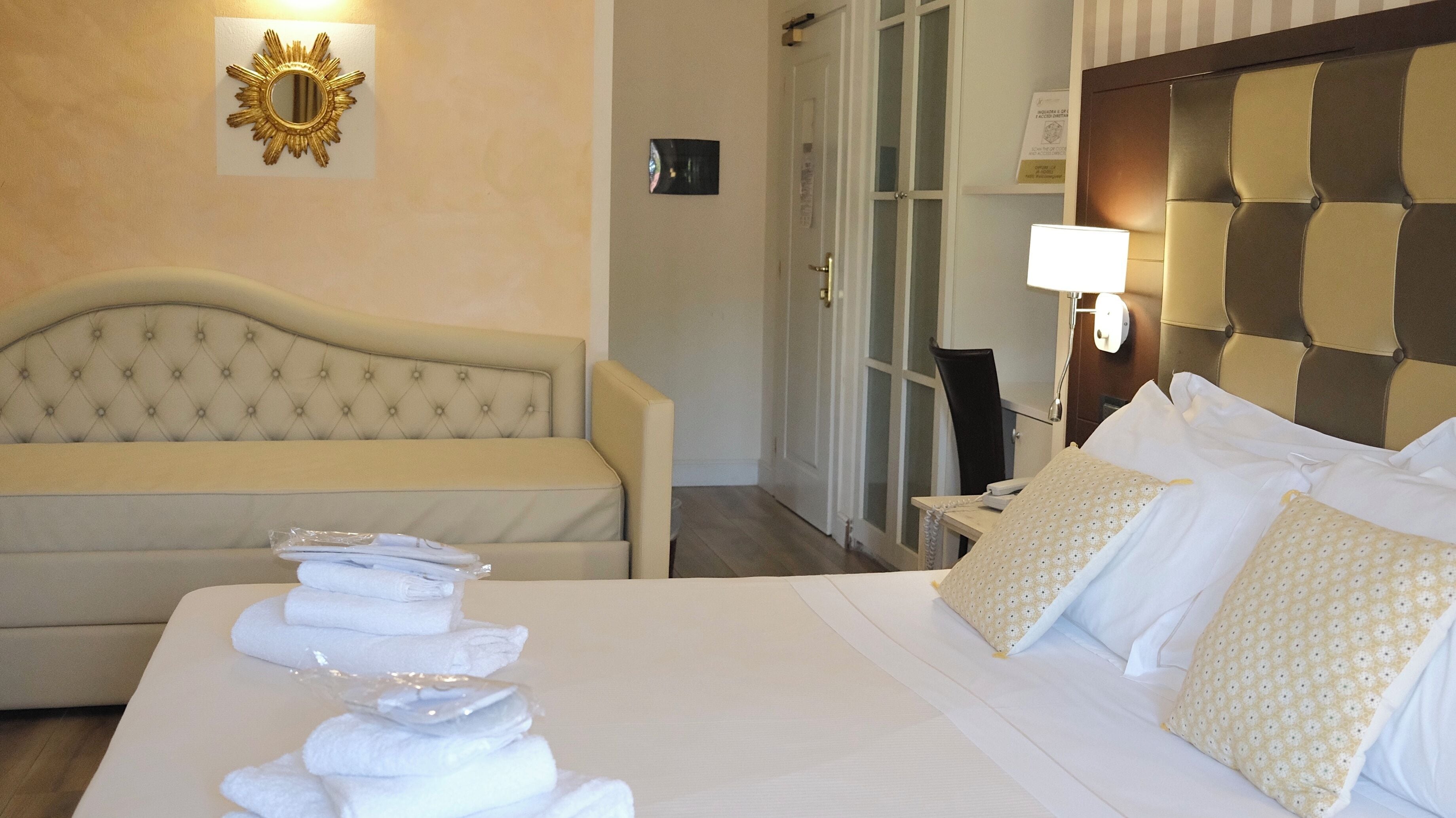 Ein Hotelzimmer mit einem Bett, einer Couch, einem an der Wand befestigten Spiegel und einer Tür.