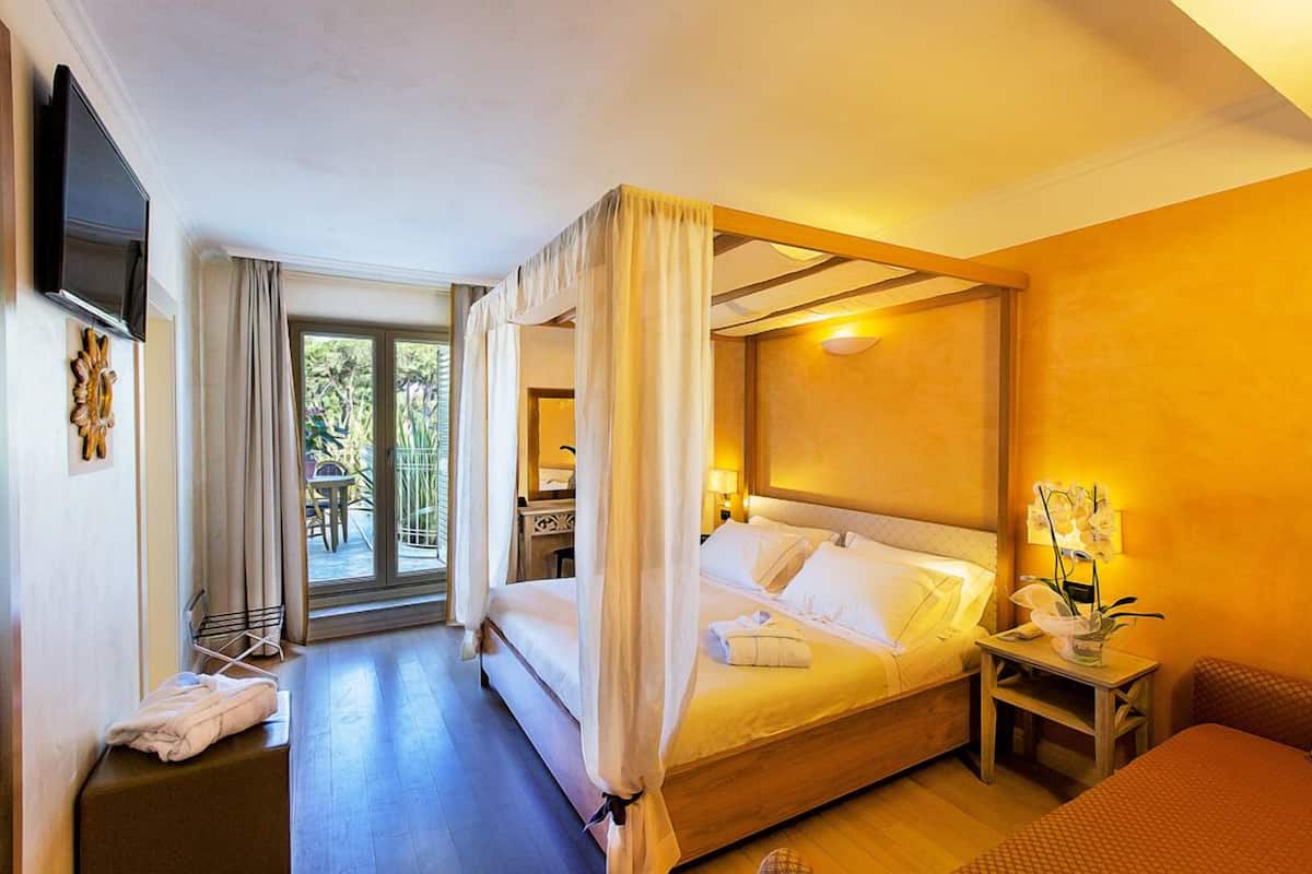 Hotelkamer met een groot bed, een televisie, nachtkastje met lamp en uitzicht op de omgeving.