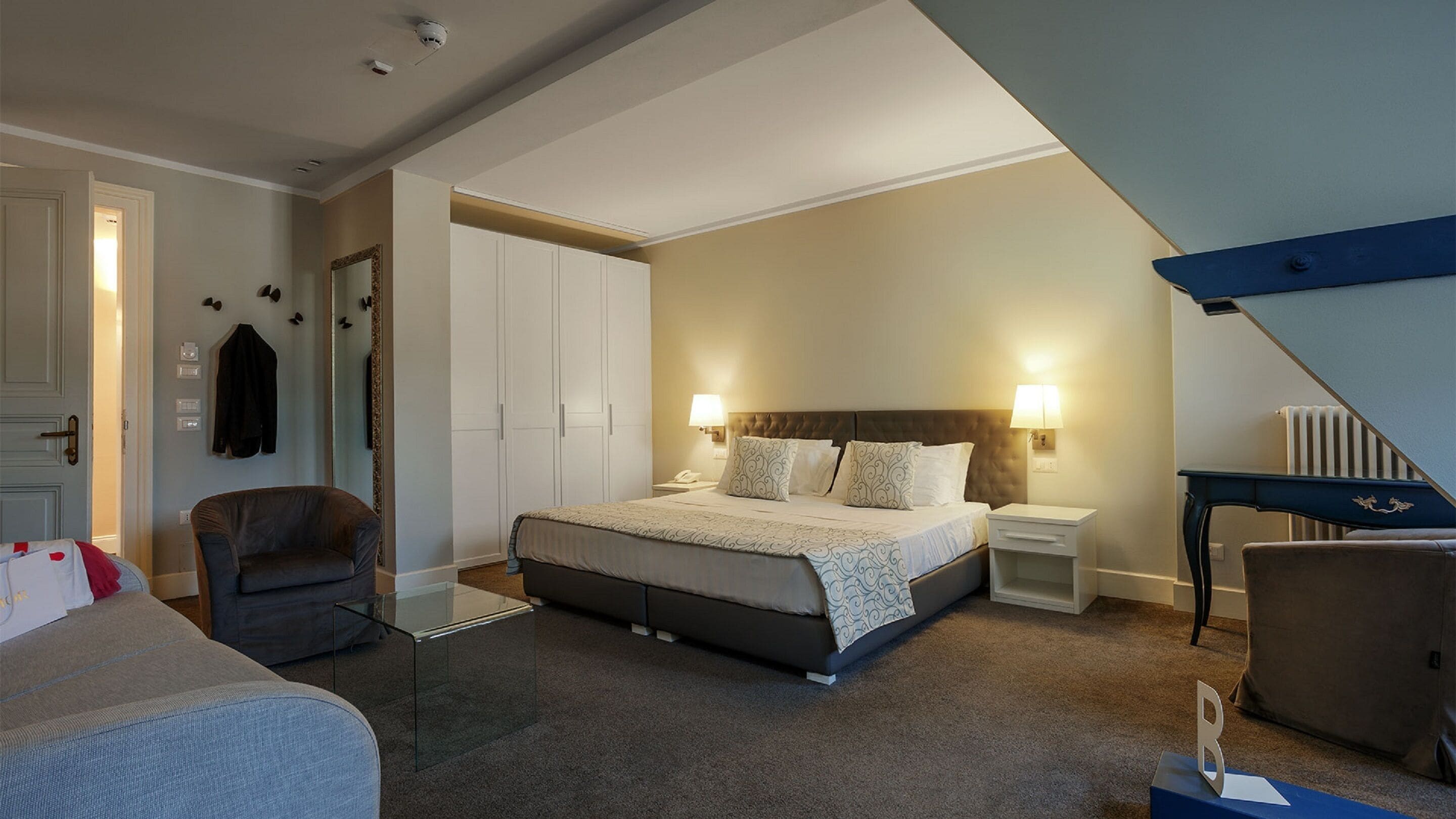 Une chambre d’hôtel avec un lit, une chaise, un bureau et une armoire.