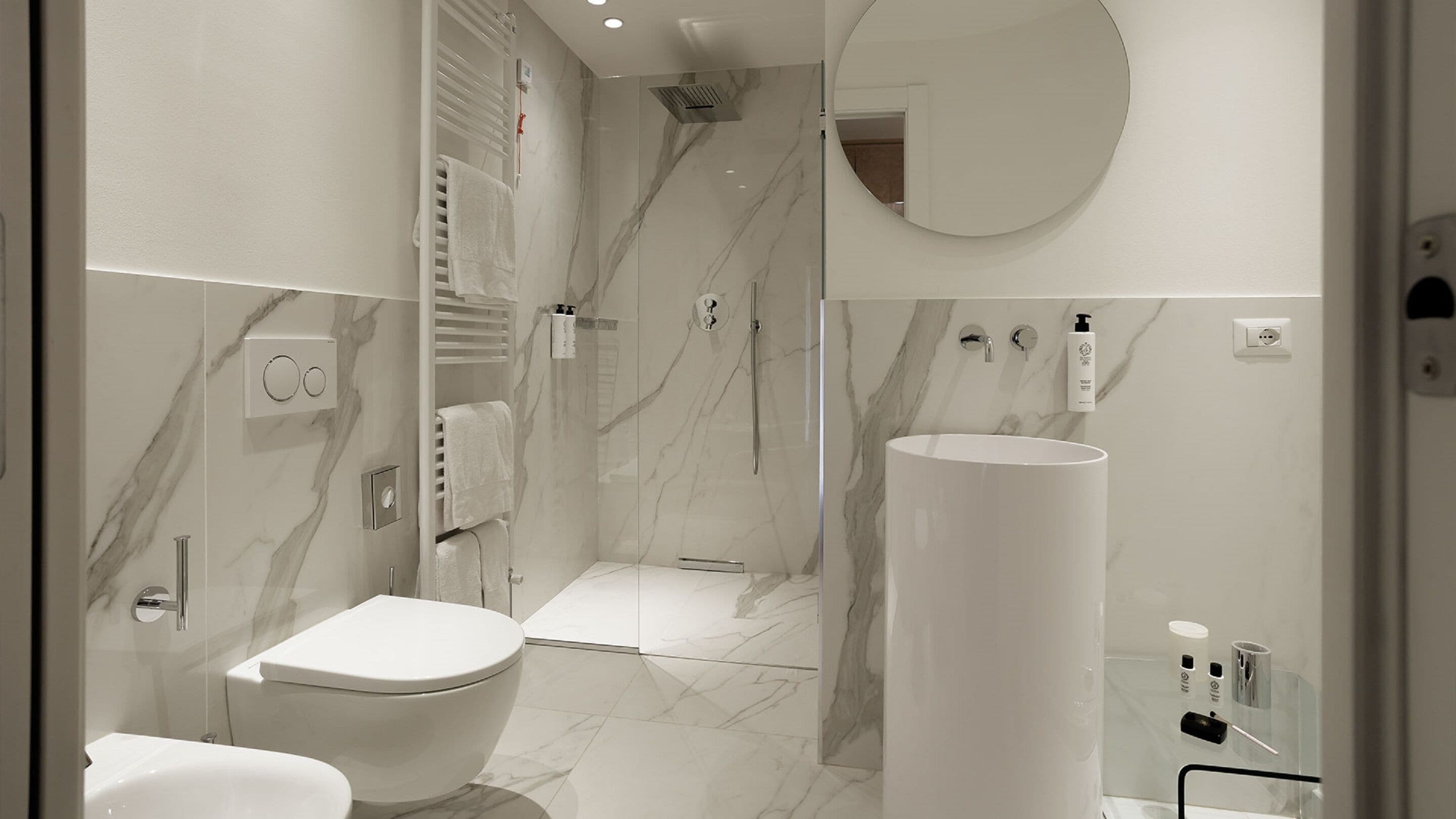 A modern bathroom with a toilet, a shower, and a sink.