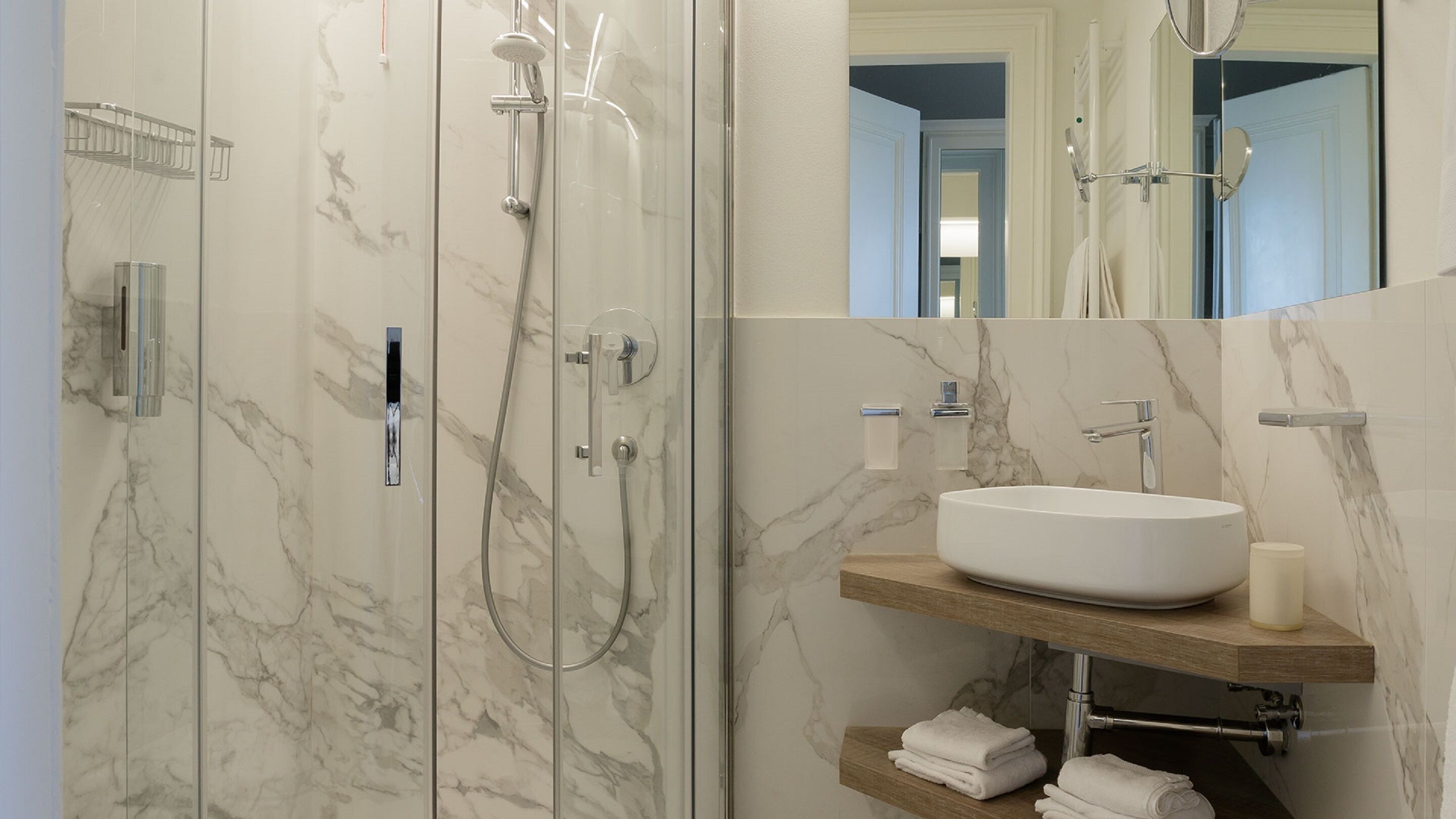 Un baño moderno con cabina de ducha de mármol, bañera independiente y tocador con lavabo y toallero.