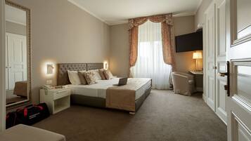 A hotel room with a bed, bedside table, lamp, and a TV on the wall.