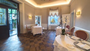A dining area with checkered flooring, white tablecloths, and a chandelier. - Camin Hotel Luino (Luino)
