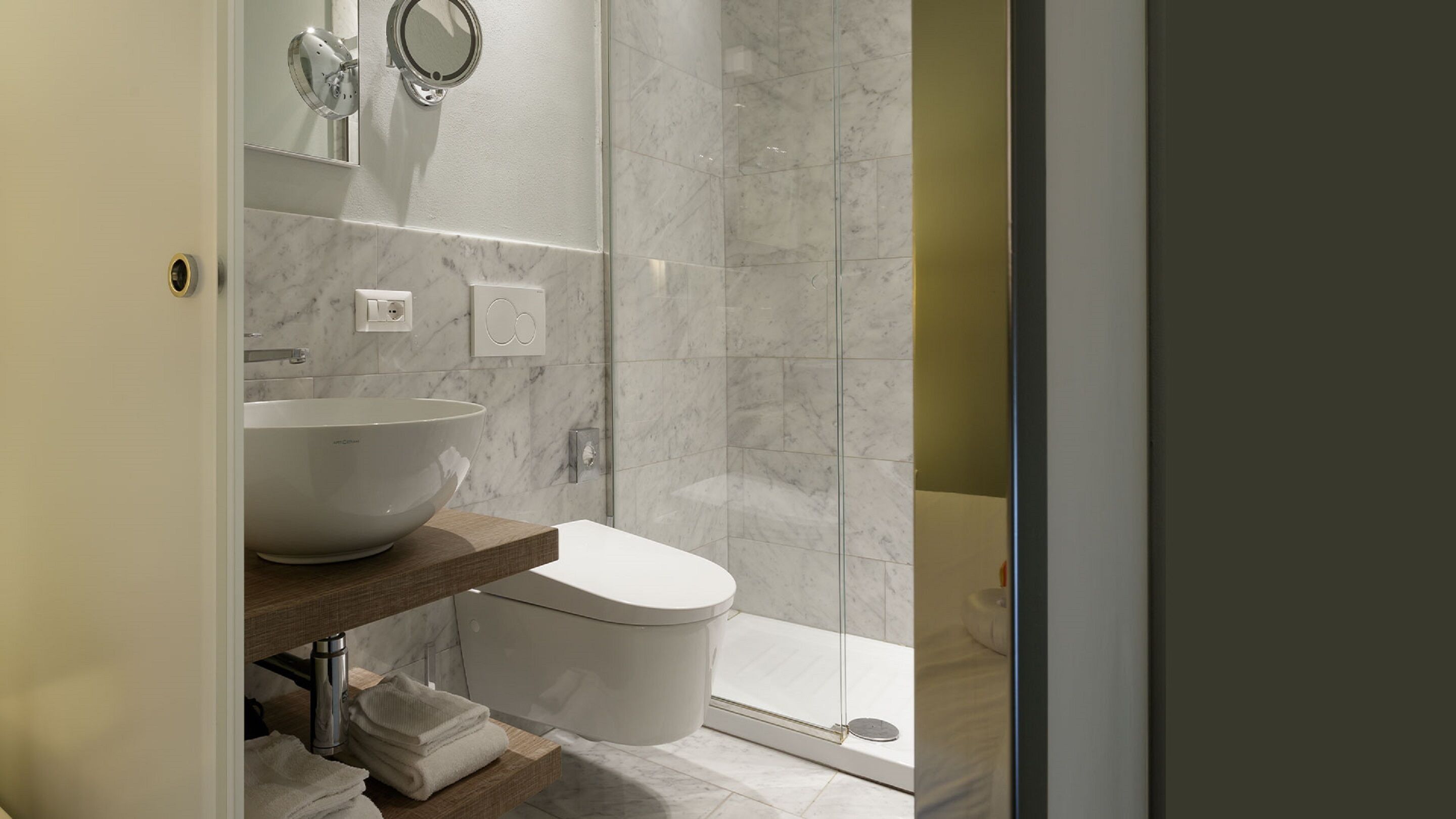 Un baño moderno con un lavamanos blanco grande, un inodoro y una ducha con cerramiento de vidrio.