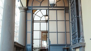 A grand entrance with a large arched doorway, a hanging light fixture, and a set of stairs leading to a door. - Camin Hotel Luino (Luino)