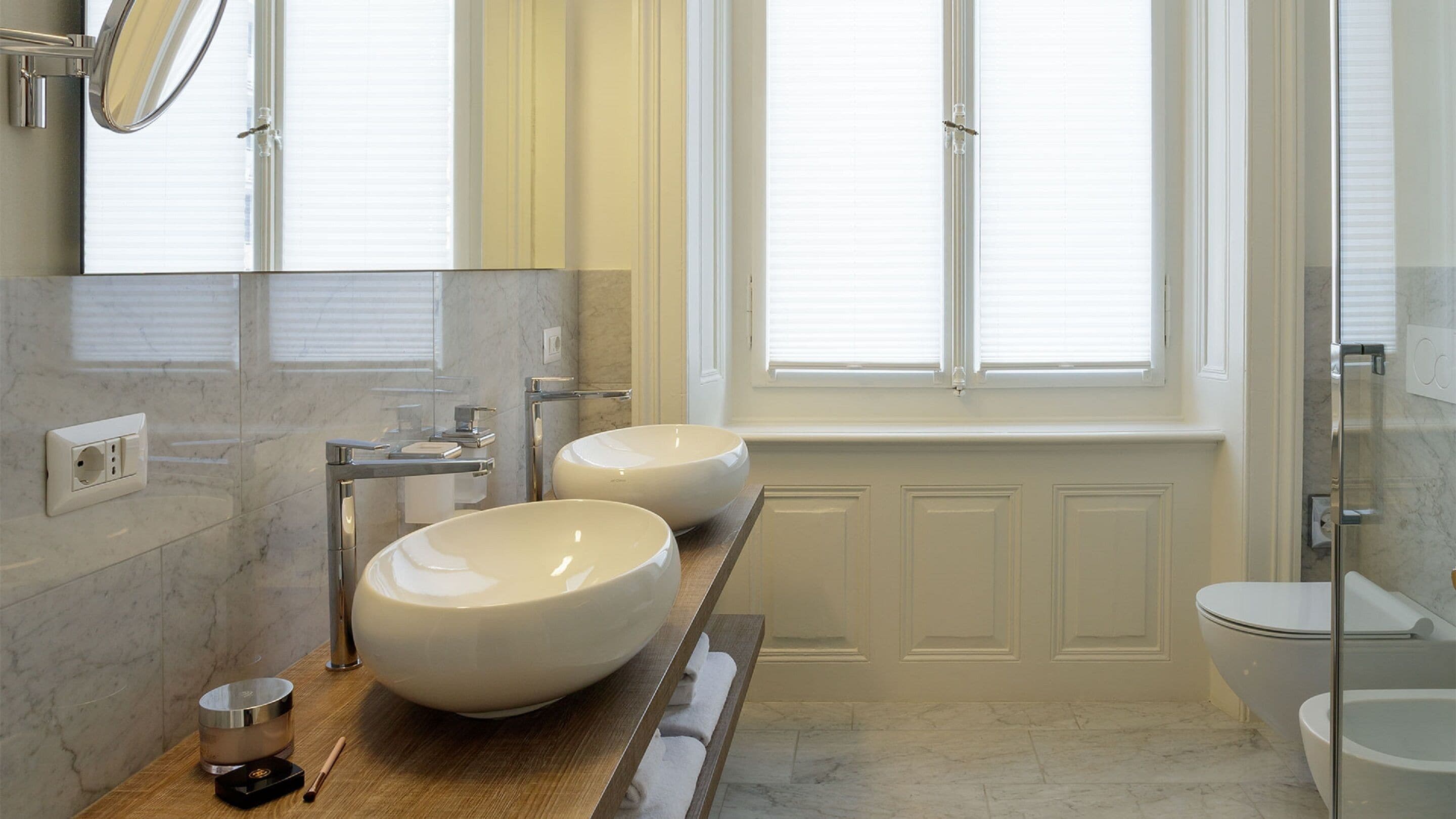 A modern bathroom with two large sinks, a mirror, and a toilet.
