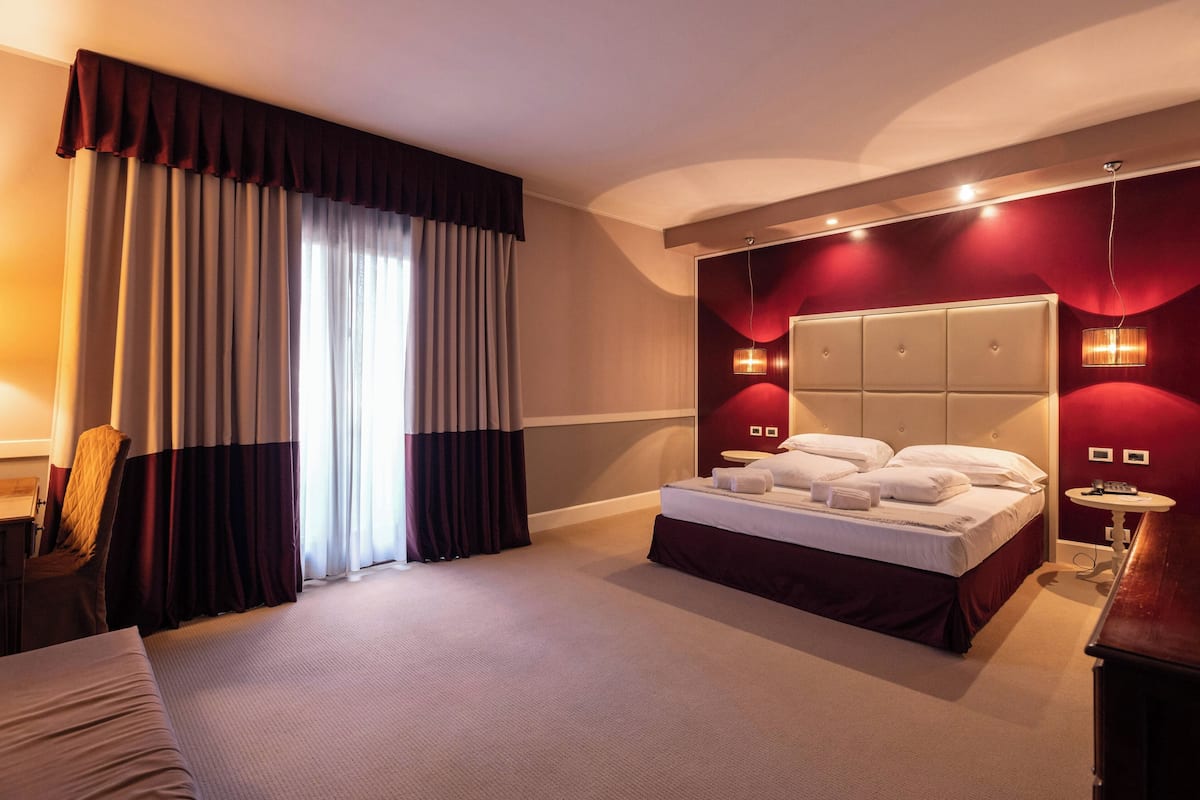 A hotel room with a large bed, a desk, and a chair.