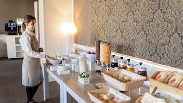 A buffet setup with various food items and a coffee machine in the background.