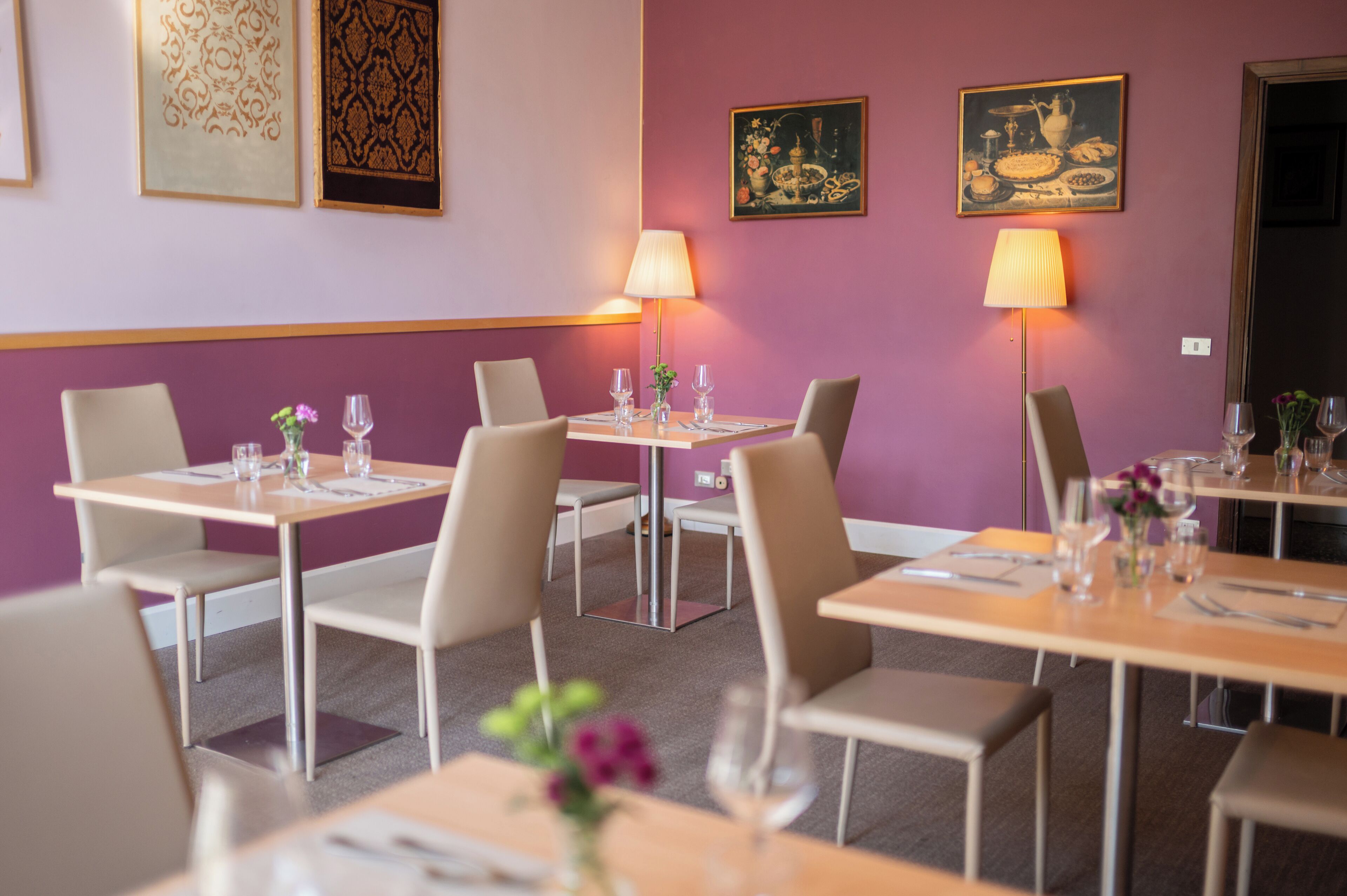 A restaurant with tables set for dining, equipped with lamps and wine glasses.
