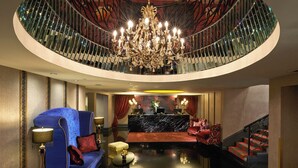 A luxurious lobby with a grand chandelier, a blue sofa, a reception desk, and a staircase. - The Scarlet Singapore (Singapore)
