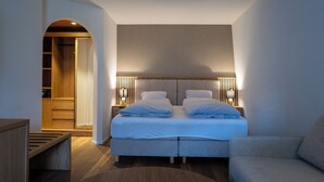 A modern bedroom with a double bed, bedside tables, a bench, and a wardrobe. - Viktoria Eden (Adelboden)
