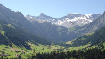 Eine gebirgige Landschaft mit einem Tal, Häusern und blauem Himmel.
