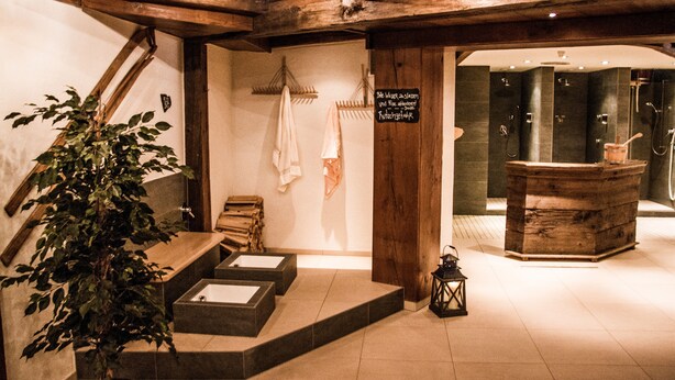A wooden staircase leading to a spa area with a sign indicating a sauna and steam room. - Viktoria Eden (Adelboden)