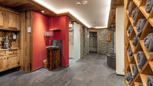 A modern bathroom with a stone wall, wooden cabinets, and a towel rack. - Sunstar Hotel Klosters (Klosters-Serneus)